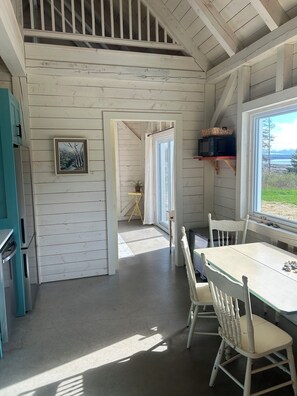 Un interior de madera con zona de comedor, cocina y vistas al exterior.