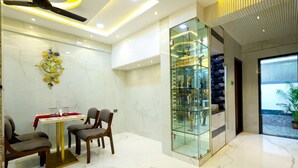 Un interior moderno con suelo de mármol, una vitrina de vidrio con esculturas y un comedor con sillas y una mesa.