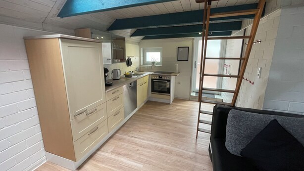 A compact kitchen with wooden cabinets, a built-in oven, and a window.