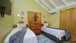 Une chambre avec deux lits, une commode, un miroir et un ventilateur de plafond.
