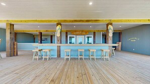 Un espace bar avec un comptoir en bois, des tabourets de bar et une enseigne indiquant « ZONE BUFFET ».