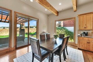 Un comedor con mesa y sillas de madera, ventanas amplias y vistas al exterior.
