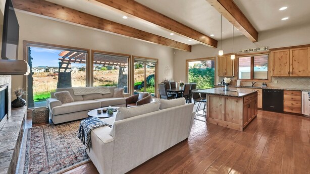 A spacious living area with a large sofa, a dining table, and a kitchen with wooden cabinets and a central island. - Ski & Golf Retreat w/ Stunning Mountain Views (Eden)