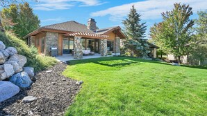 A modern house with a stone facade, a covered patio, and a well-maintained lawn. - Ski & Golf Retreat w/ Stunning Mountain Views (Eden)