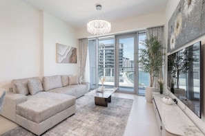 A modern living room with a sofa, coffee table, and a large window with a view of buildings and water.