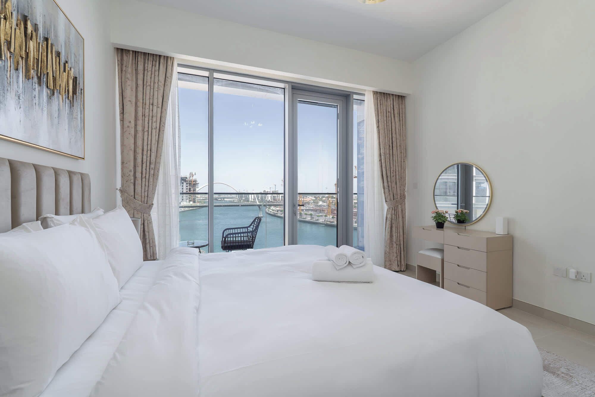 Habitación de hotel con una cama grande, vista a un puente y un paisaje urbano.