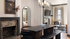 Ein modernes Wohnzimmer mit Kamin aus Stein, einem großen Spiegel, einer Bar mit Sitzgelegenheiten und einem an der Wand befestigten Fernseher.