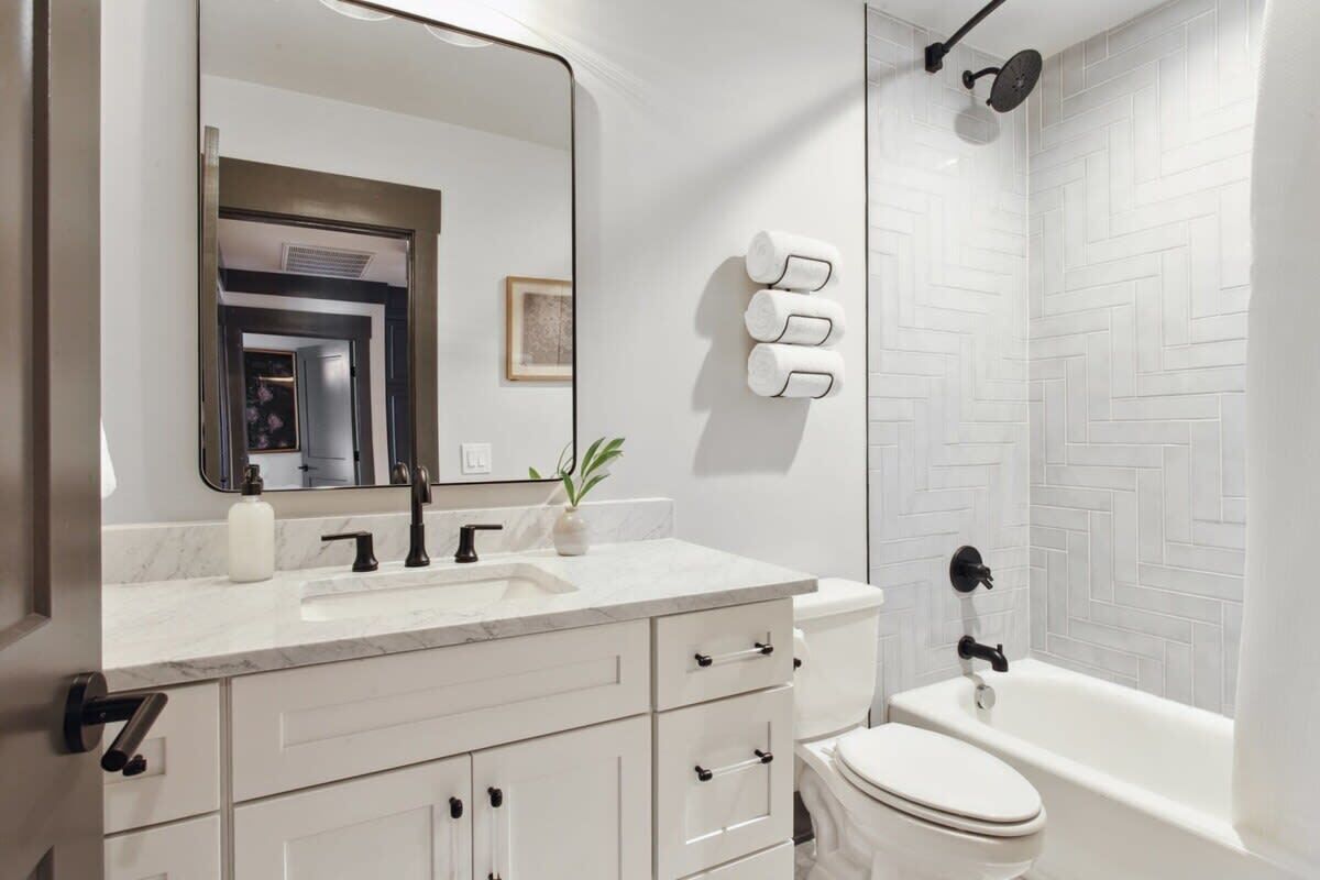Une salle de bain moderne avec un meuble-lavabo blanc, un grand miroir, des toilettes et un espace douche.