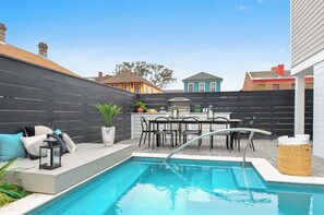Un jardin avec une piscine, un espace salon extérieur et un coin cuisine.