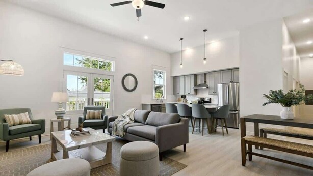 Un salon moderne avec un canapé, des poufs et une table basse. Il y a également un coin cuisine avec une table à manger et des chaises.
