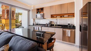 A modern kitchen with a large island, stainless steel appliances, and a view of a cityscape through a sliding glass door.