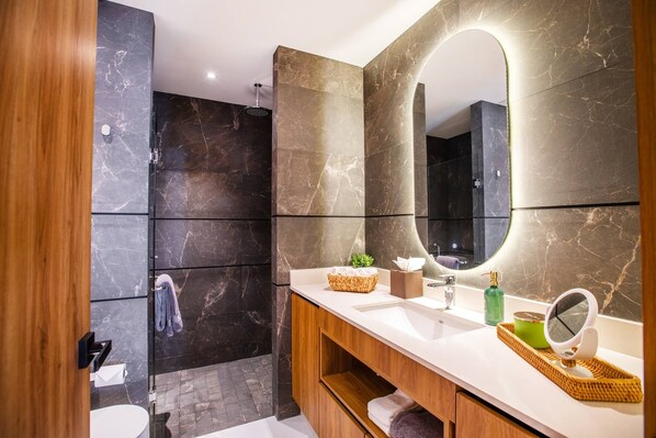 Un baño moderno con ducha, tocador con espejo y perchero.