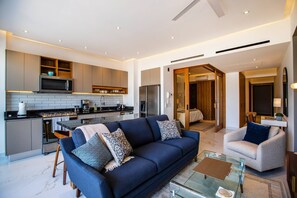 A modern living room with a sofa, armchairs, and a glass coffee table.