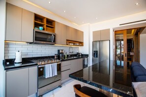 A modern kitchen with a central island, built-in appliances, and a seating area.