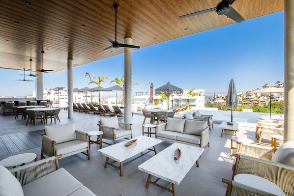 A rooftop terrace with outdoor seating, a pool, and a view of the city.