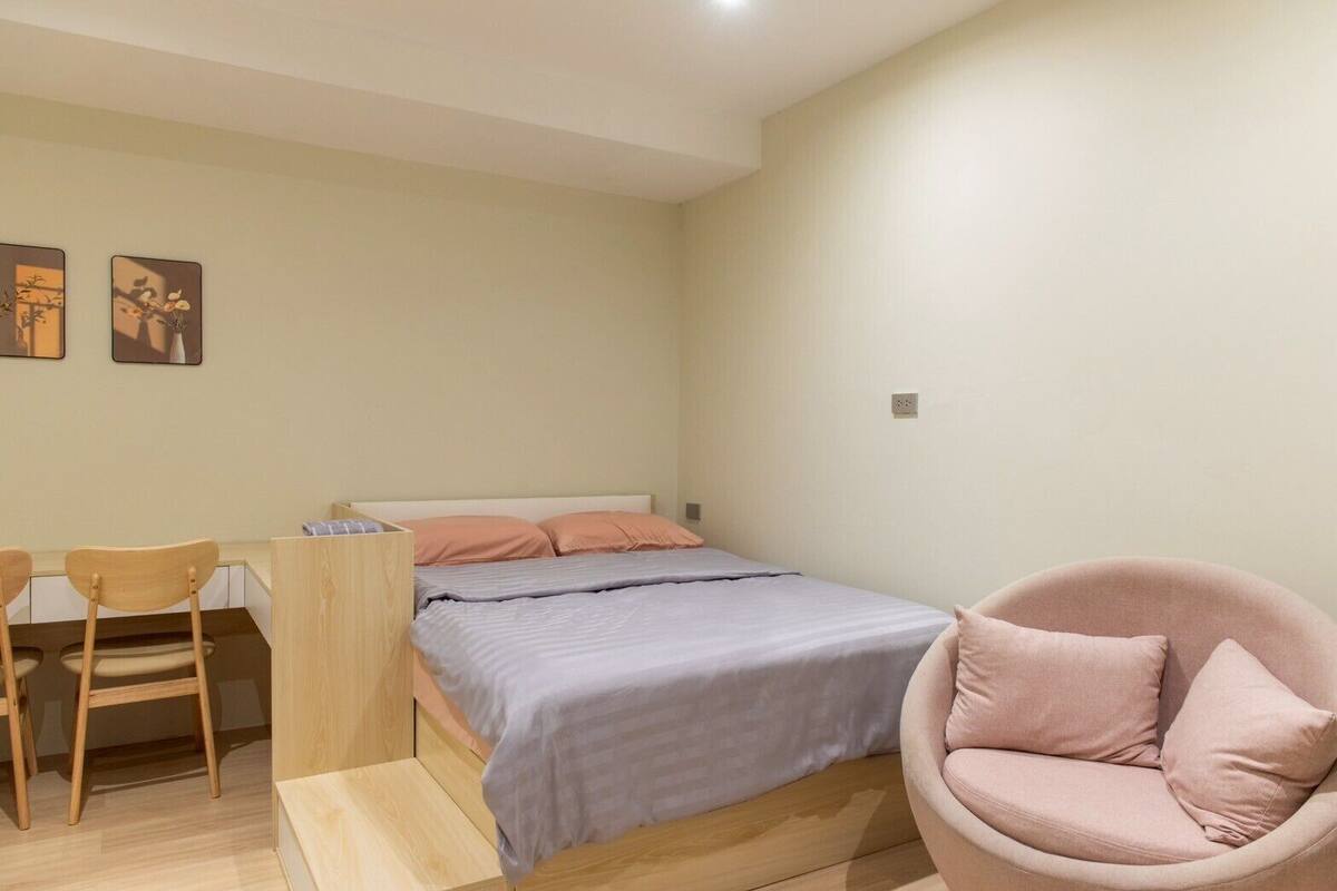 A bedroom with a bed, a desk, a chair, and a sofa.