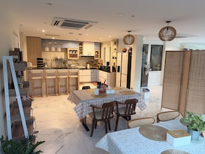 Una cocina moderna con electrodomésticos integrados, un comedor con mesa y sillas, y vistas al espacio de estar contiguo.