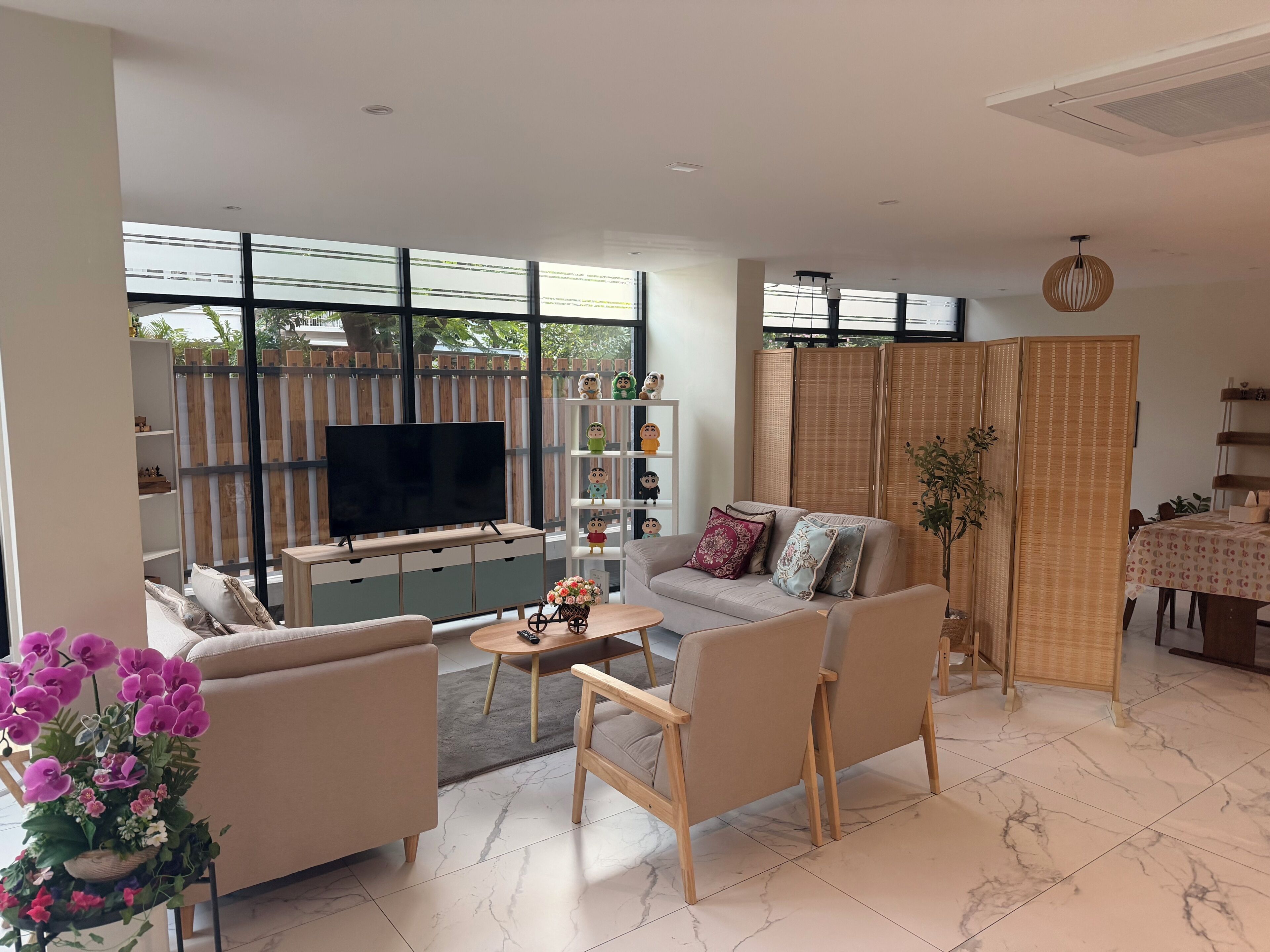 Una sala moderna con televisor, sofá, mesa de centro y plantas decorativas.