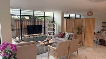 Una sala moderna con televisor, sofá, mesa de centro y plantas decorativas.
