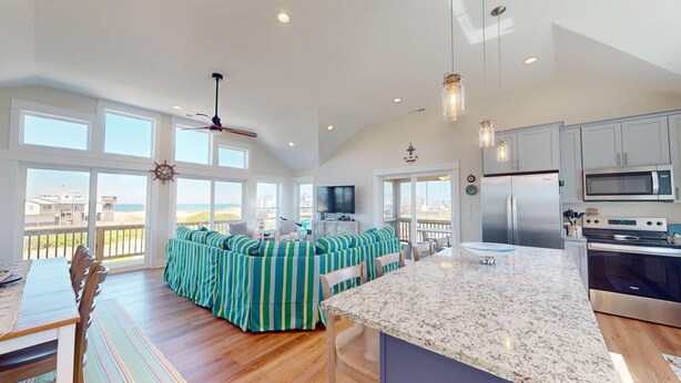 Una cocina amplia con una isla grande, un comedor con vistas y una sala de estar con mobiliario a rayas.