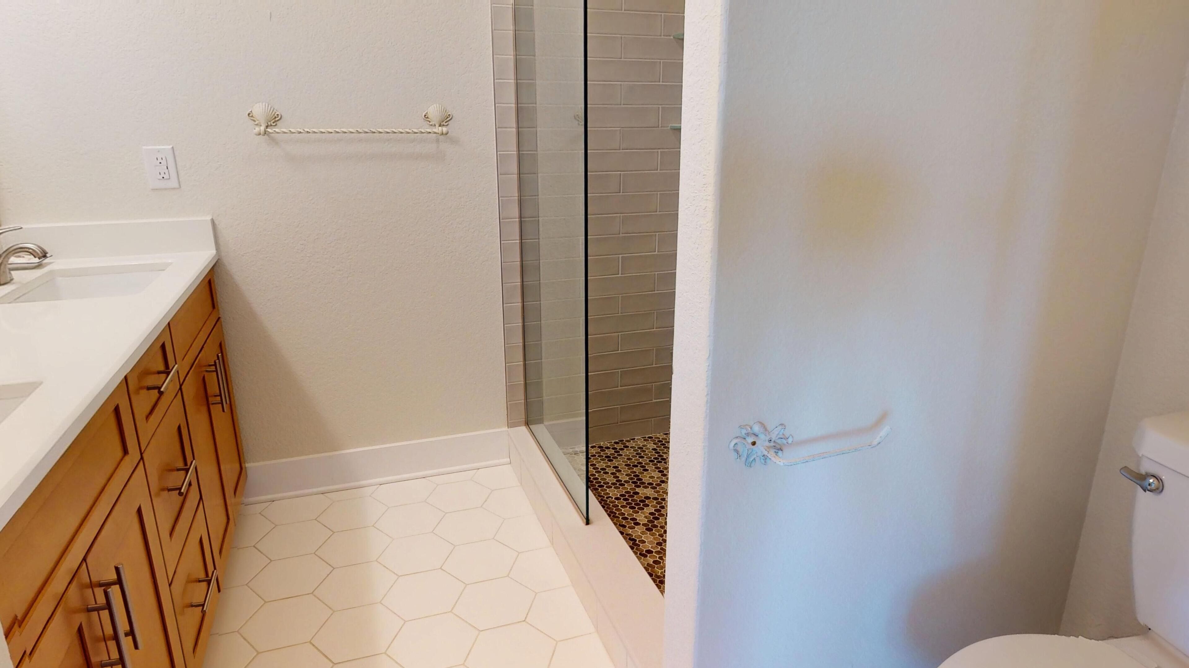 A bathroom with a white sink, wooden cabinets, a glass shower enclosure, and a toilet.