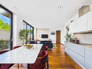 Une cuisine moderne avec un coin repas, de grandes fenêtres et une vue sur la verdure environnante.
