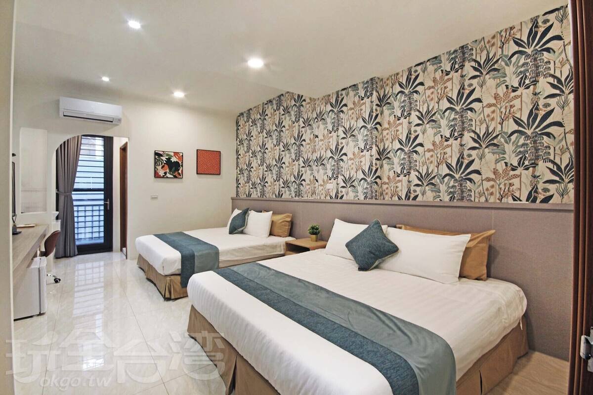 Ein Hotelzimmer mit zwei Betten, einem Schreibtisch und einem Stuhl.