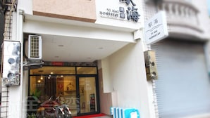 Fachada con un letrero que dice 'Yi Hai Homestay' y una puerta con persiana cerrada.