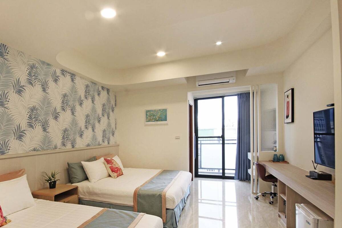 Ein Hotelzimmer mit zwei Betten, einem großen Fenster, einer Klimaanlage und einem Schreibtisch mit Fernseher.