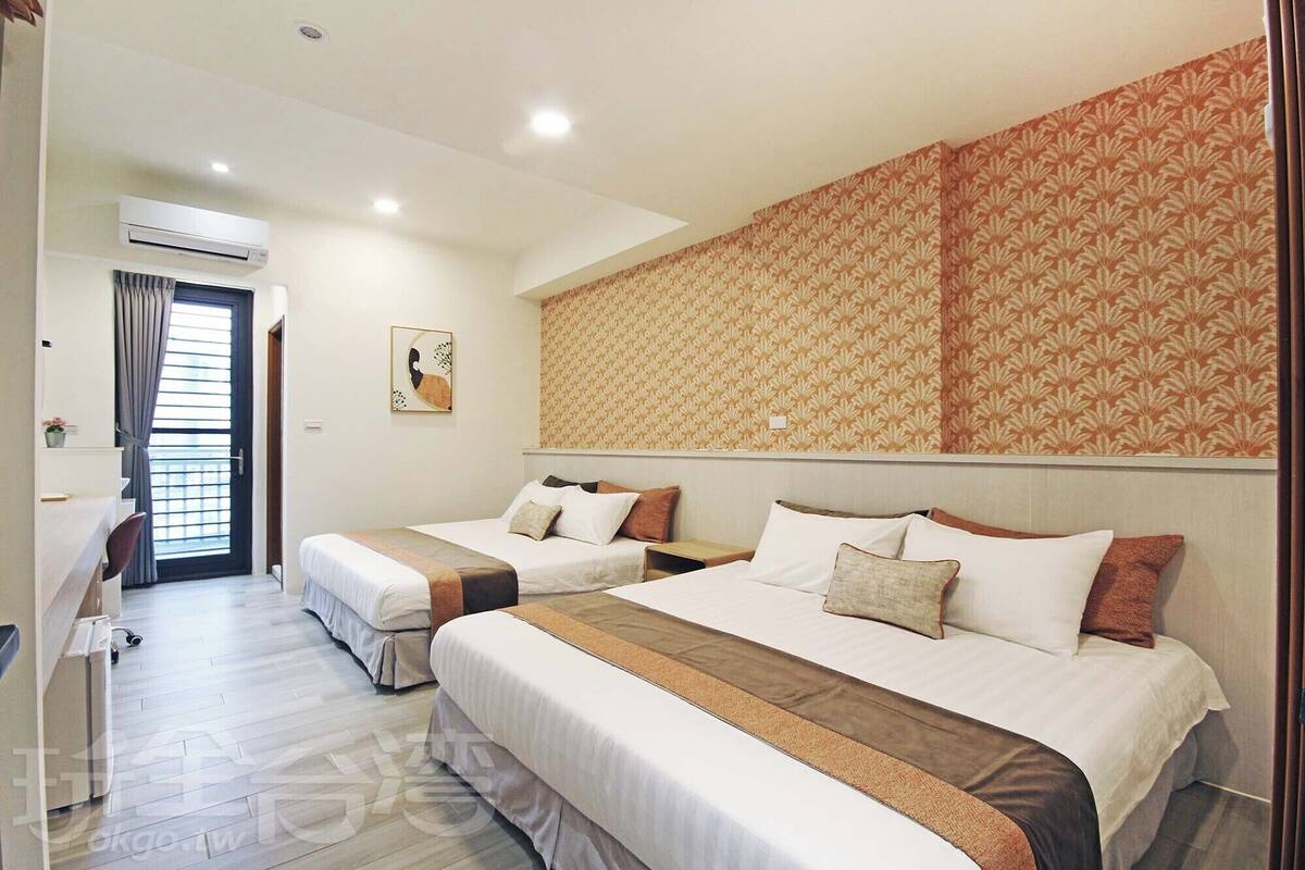 Ein Hotelzimmer mit zwei Betten, einem Schreibtisch und einer Klimaanlage.