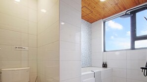 Un baño moderno con azulejos blancos, techo de madera, ducha y bañera.