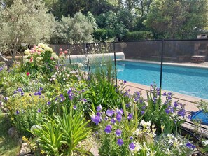 A swimming pool surrounded by lush greenery and various flowering plants. - Beautiful villa, green setting with swimming pool, quiet 800m from the center (Saint-Rémy-de-Provence)