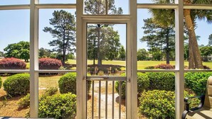 A conservatory with a view of a landscaped garden, including a pathway and various shrubs.