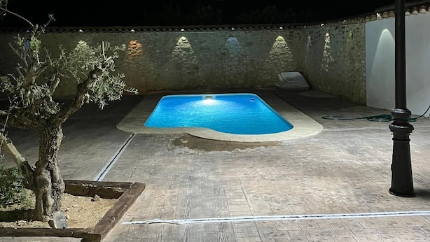 A rectangular swimming pool with a tiled deck, surrounded by a low stone wall and a single street lamp. - El Molino De Alatoz  (Alatoz)
