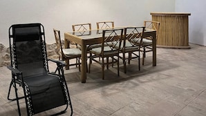 A dining area with a table and chairs, a black chair, and a wooden cabinet. - El Molino De Alatoz  (Alatoz)