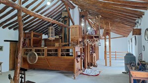 A rustic wooden interior with exposed beams, a large wooden cabinet, and various antique mechanical devices. - El Molino De Alatoz  (Alatoz)
