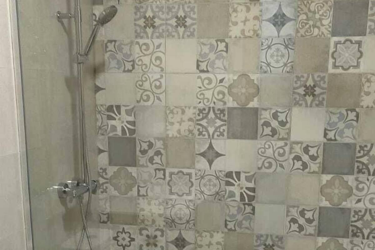 A bathroom with a shower, toilet, and wooden flooring.