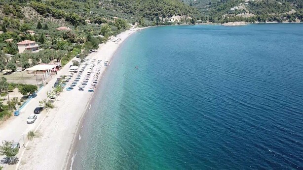 Vista aérea de una zona costera con playa, coches aparcados y edificios.