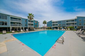 A swimming pool with lounge chairs and a building with balconies. - Sea Oats 105h 3 Bedroom Condo (Gulf Shores)