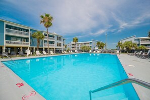 A swimming pool with lounge chairs and a building with balconies. - Sea Oats 105h 3 Bedroom Condo (Gulf Shores)