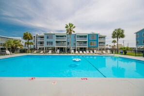 A swimming pool with lounge chairs and a building with balconies in the background. - Sea Oats 105h 3 Bedroom Condo (Gulf Shores)