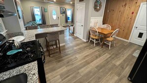 Een keuken met granieten aanrecht, een fornuis en een eethoek met een houten tafel en stoelen.