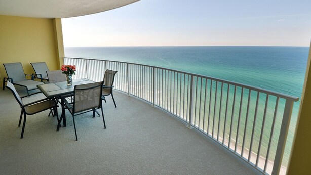 Un balcone con tavolo e sedie, affaccio su una limpida vista sull'oceano.