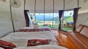 A tent-style room with a bed, a sofa, and a fan. - Koya Homestay (Mae Rim)