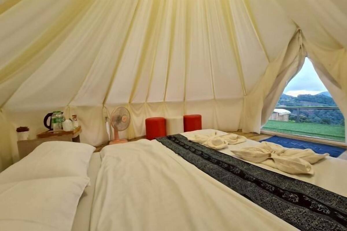 A tent-style room with a bed, a fan, and a window with a view.