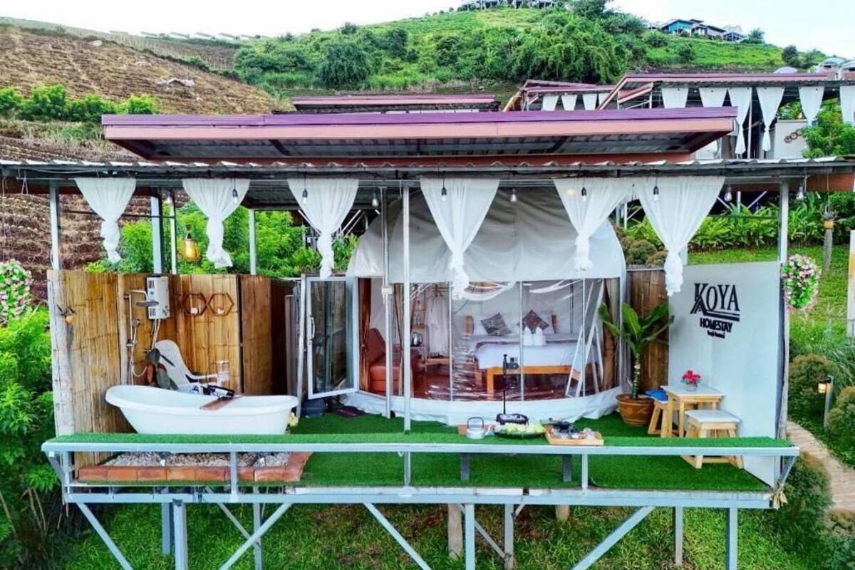 A small, enclosed outdoor structure with a bed, a sink, and a table.
