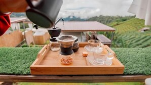 A wooden tray with a coffee maker, a glass carafe, and a glass mug on a table with artificial grass. - Koya Homestay (Mae Rim)