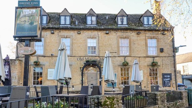 Un edificio de piedra tradicional con un letrero que indica 'Old Manse Hotel' y 'Greene King'.