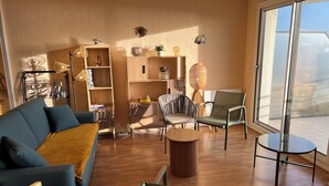 Een moderne woonkamer met een bank, stoelen, een salontafel en een boekenkast.