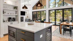 A modern kitchen with a large island, built-in shelves, and pendant lighting.